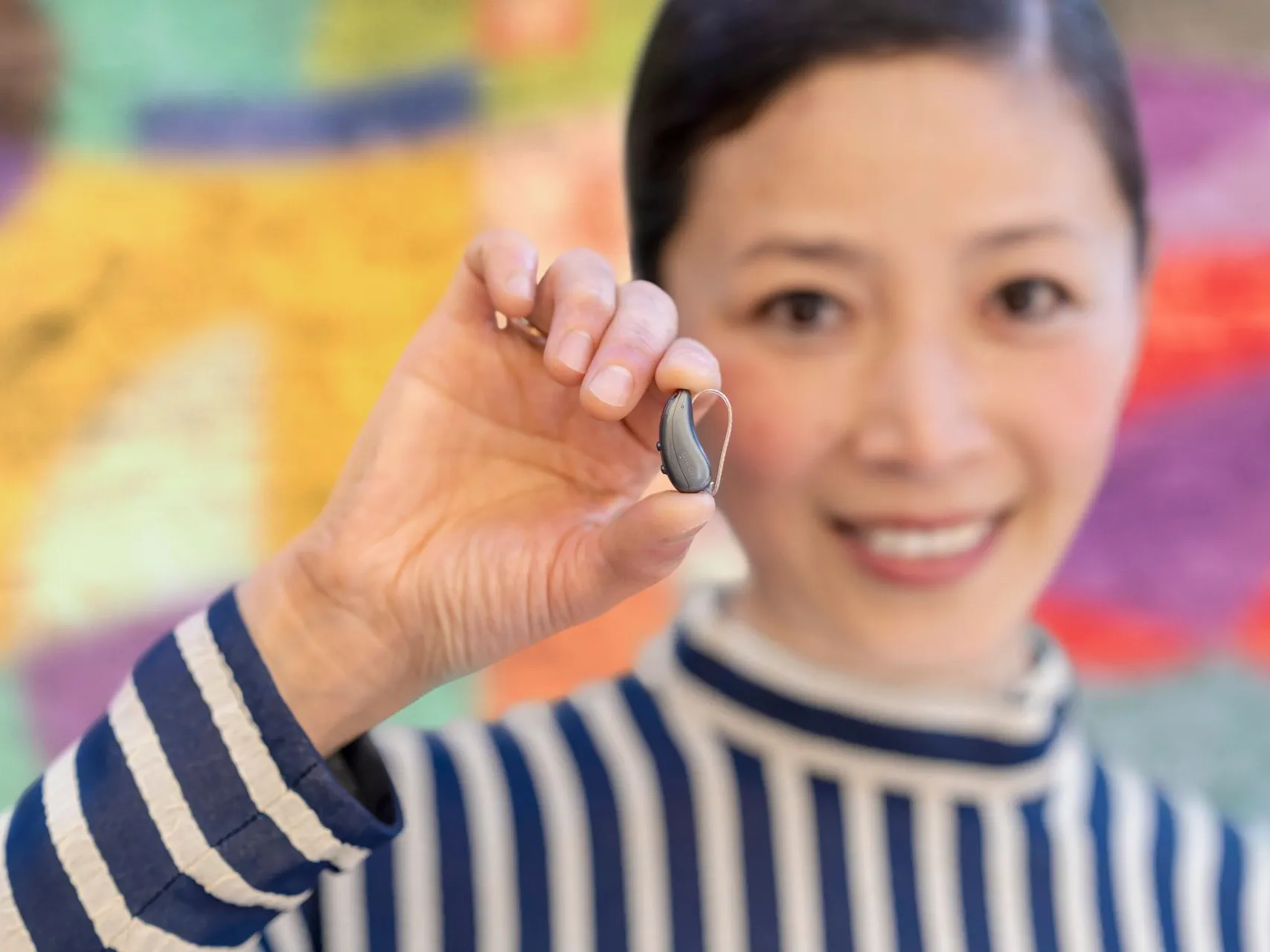 Woman showing Signia IX hearing aids in hand truly showing the small size. 